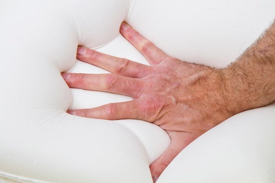 Hand pushing down on a memory foam Mattress